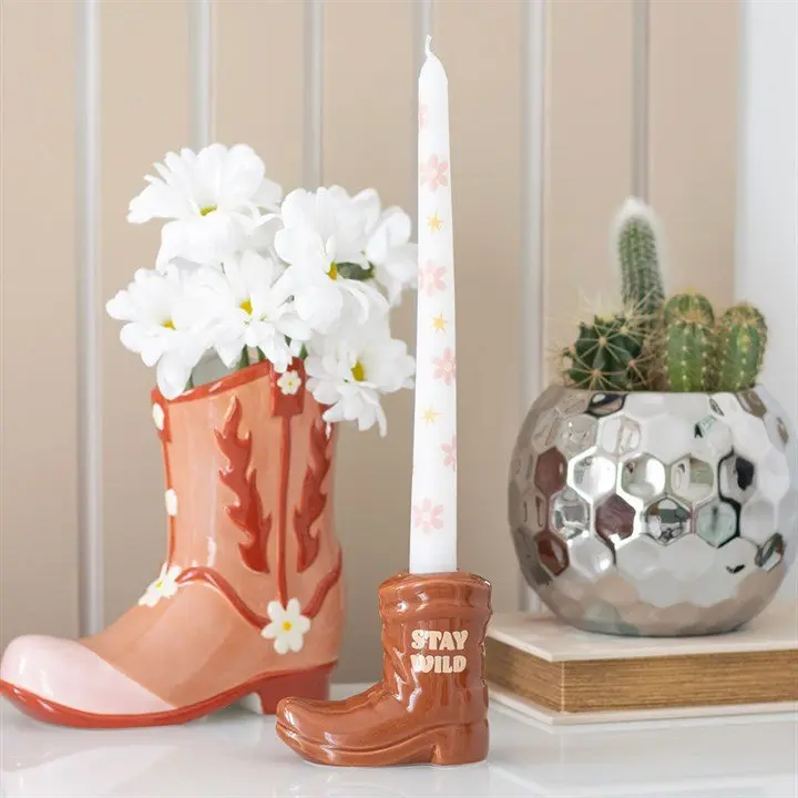 Brown cowboy boot holding a white floral taper candle